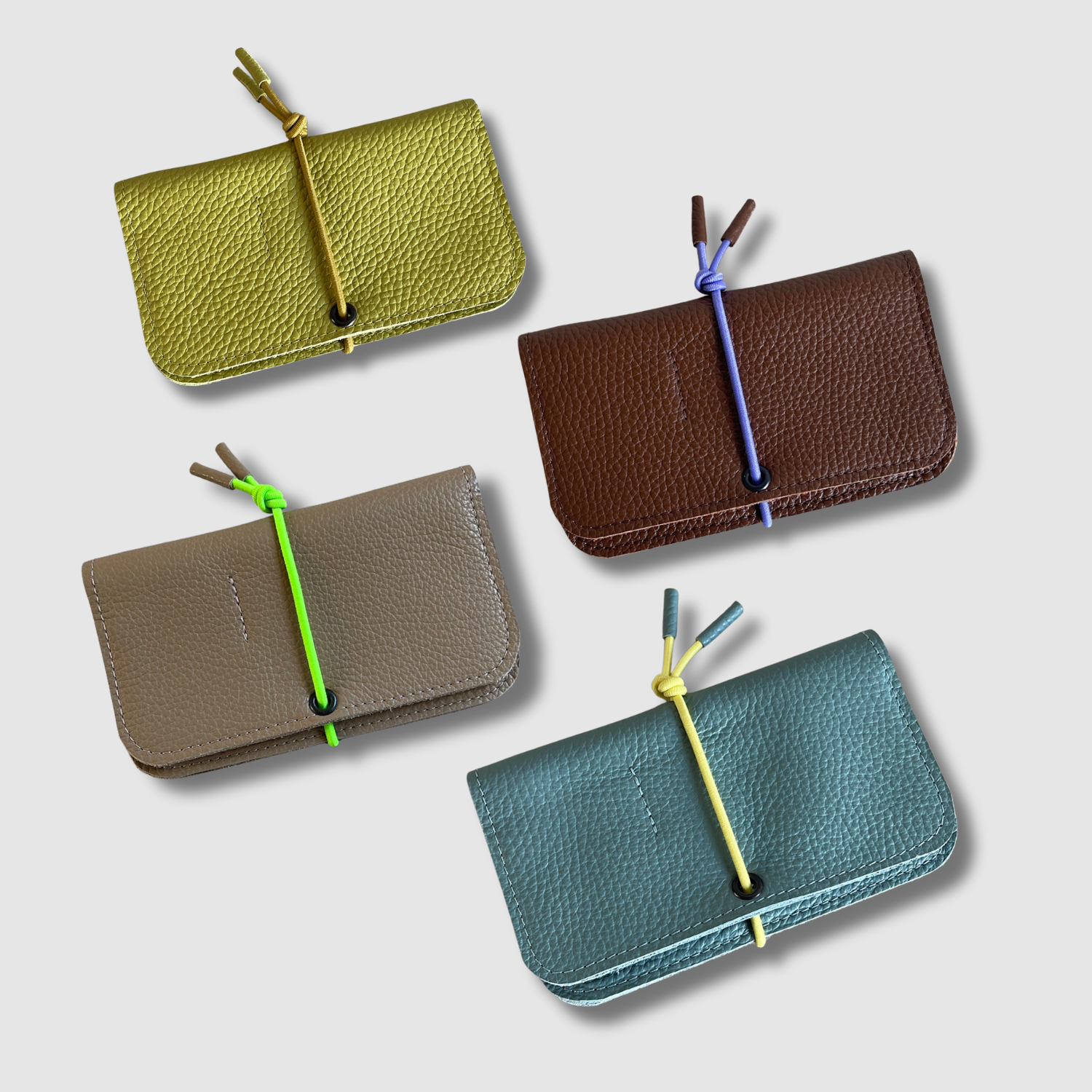 Multiple leather knot wallets in green and brown tones, each with front flap and cord tie
