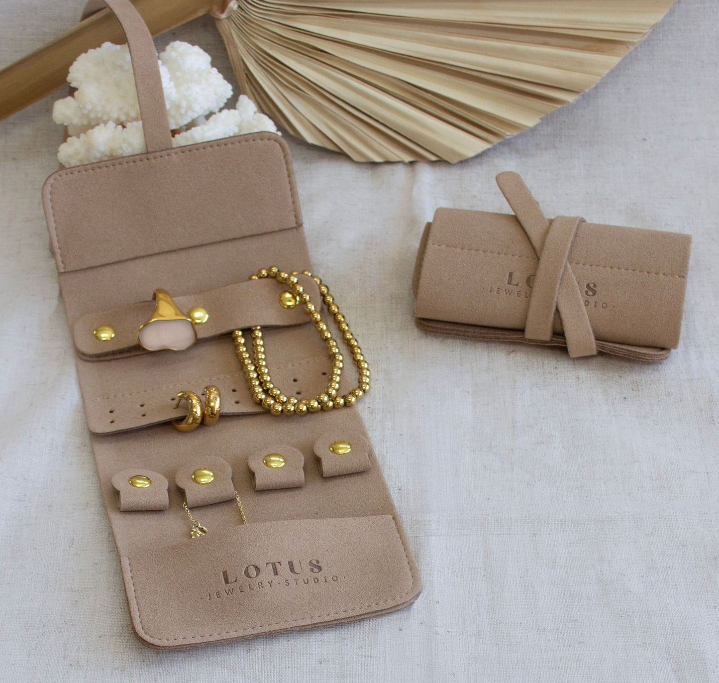 Taupe suede travel jewelry roll with snap compartments for rings, bracelet, and necklace
