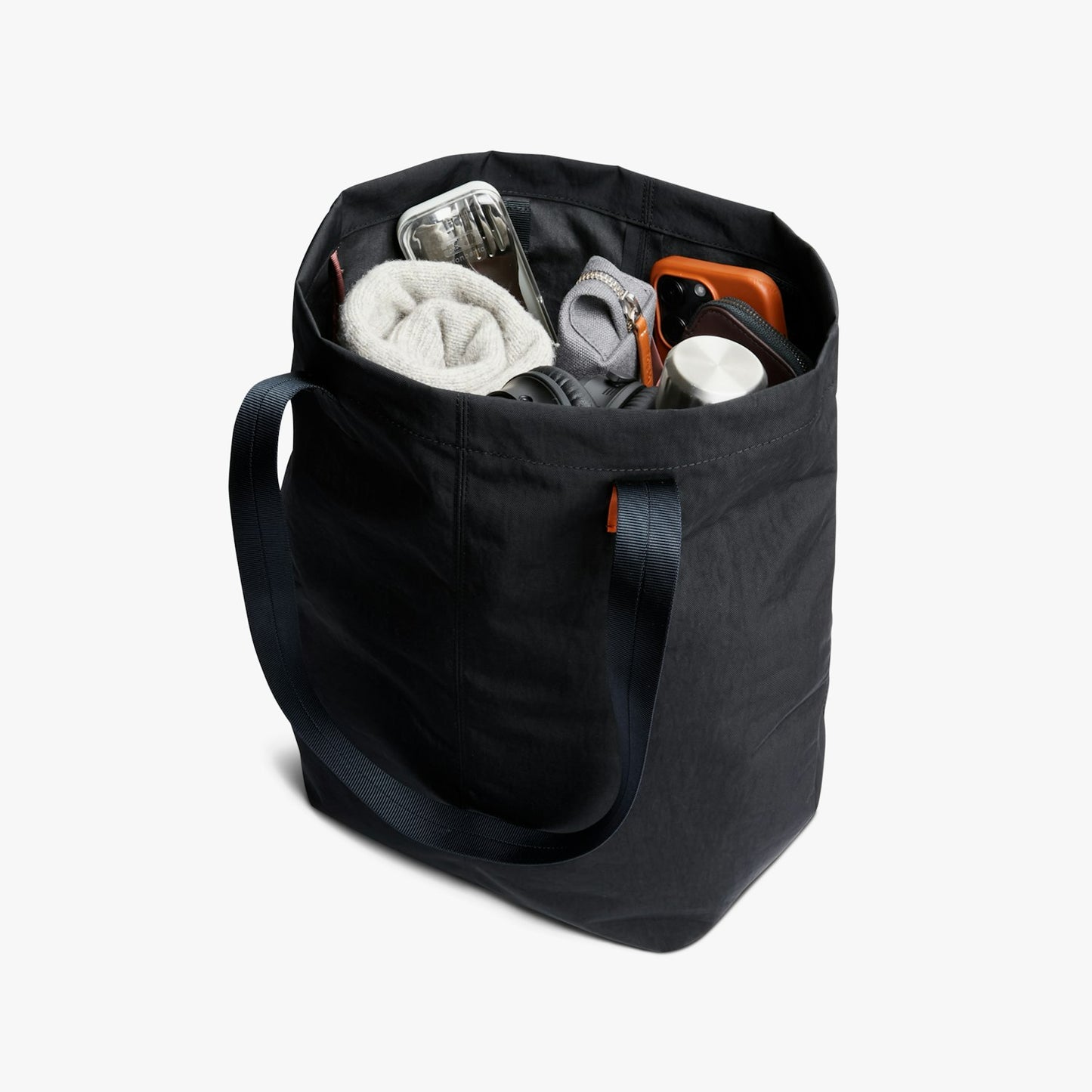 City tote bag open top showing interior pockets and contents including a folded towel.