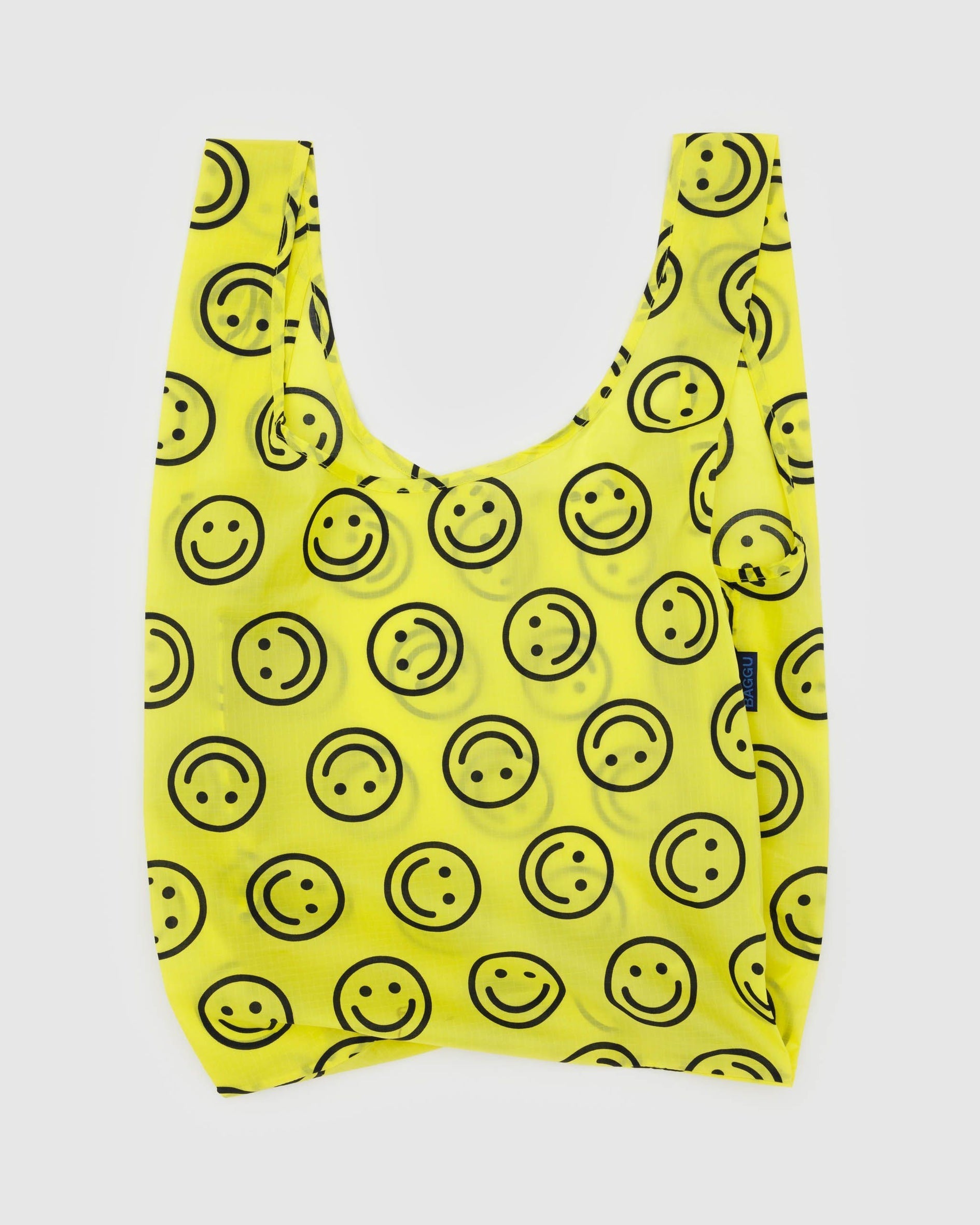 Reusable tote bag in bright yellow with smiley-face print and short U-shaped handles.