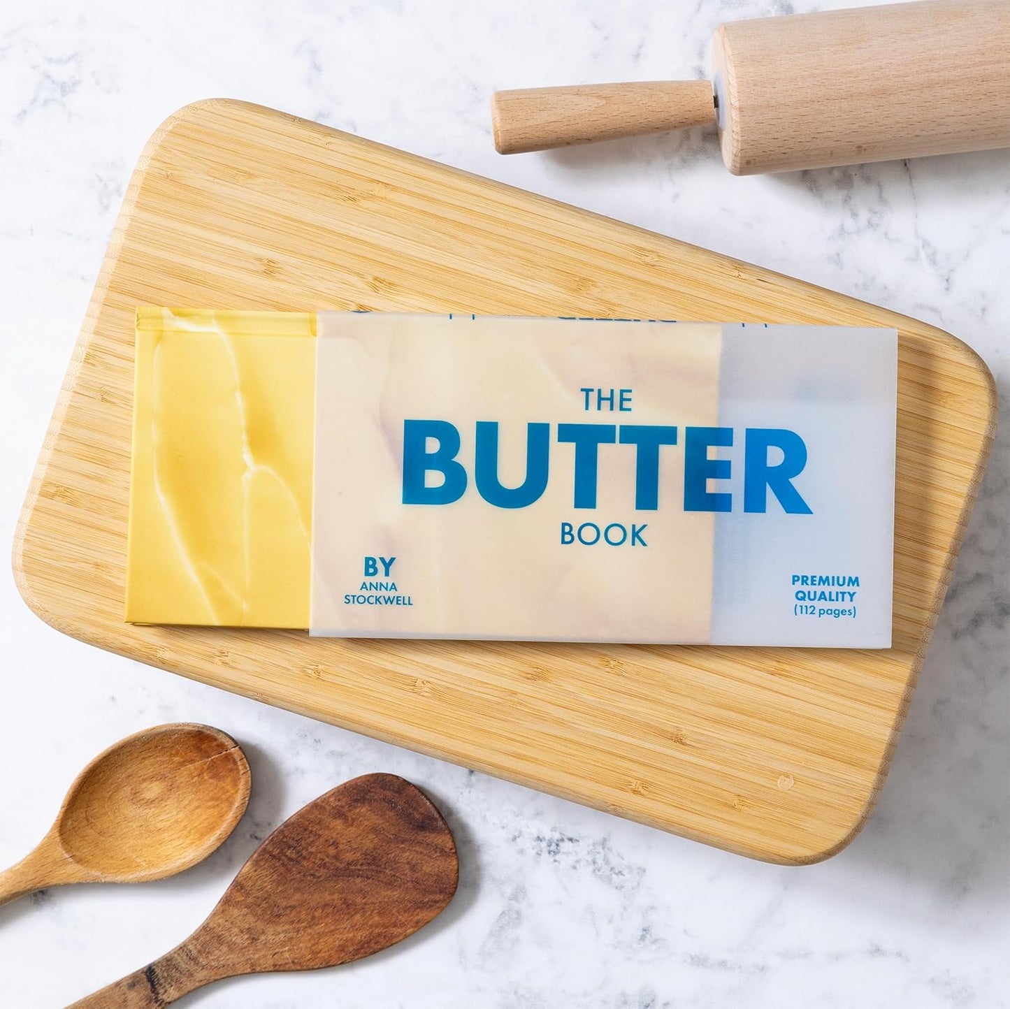 The Butter Book cookbook with wooden board and yellow butter wrapped in parchment.
