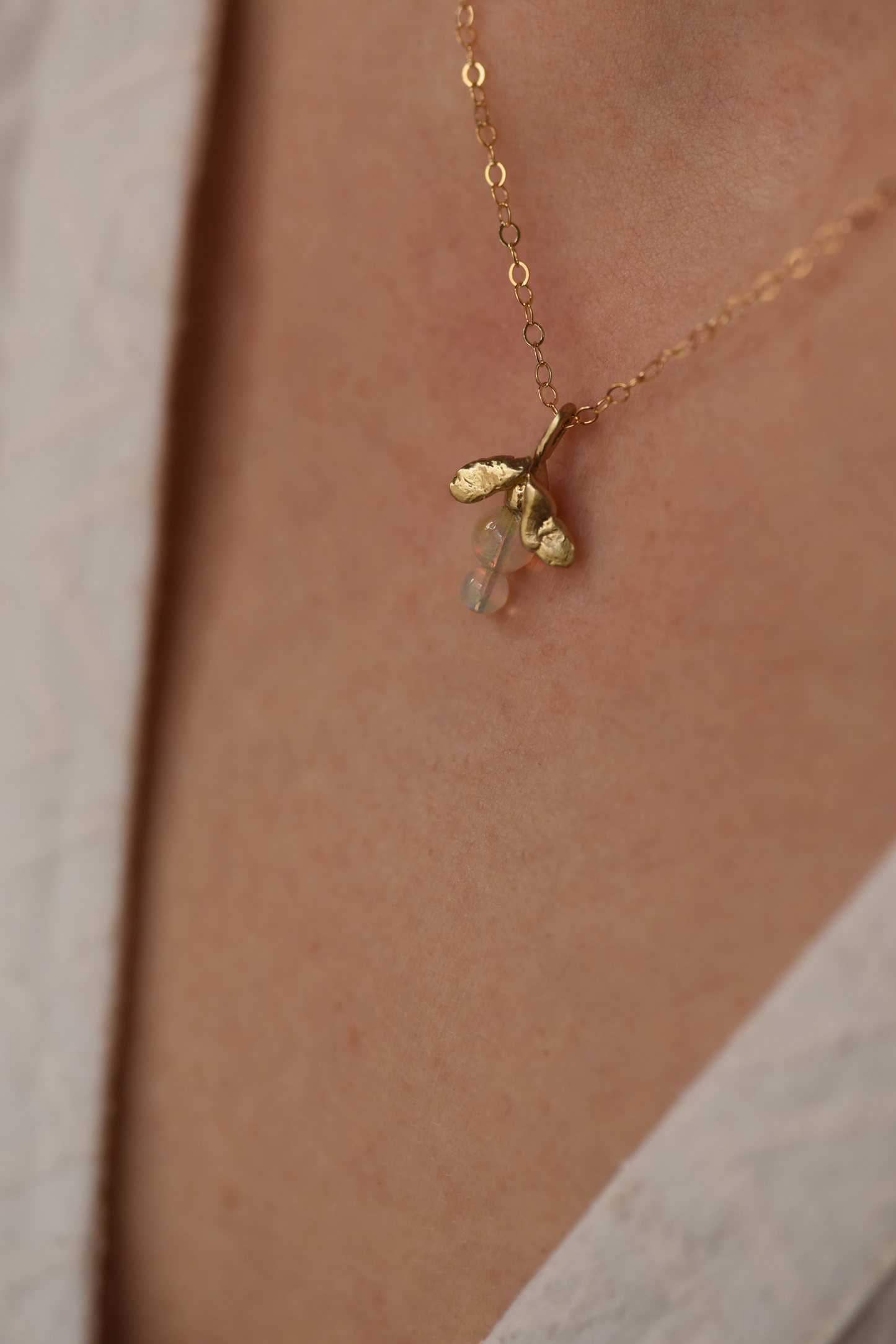 Gold pendant necklace with two leaf charms and a green opal drop