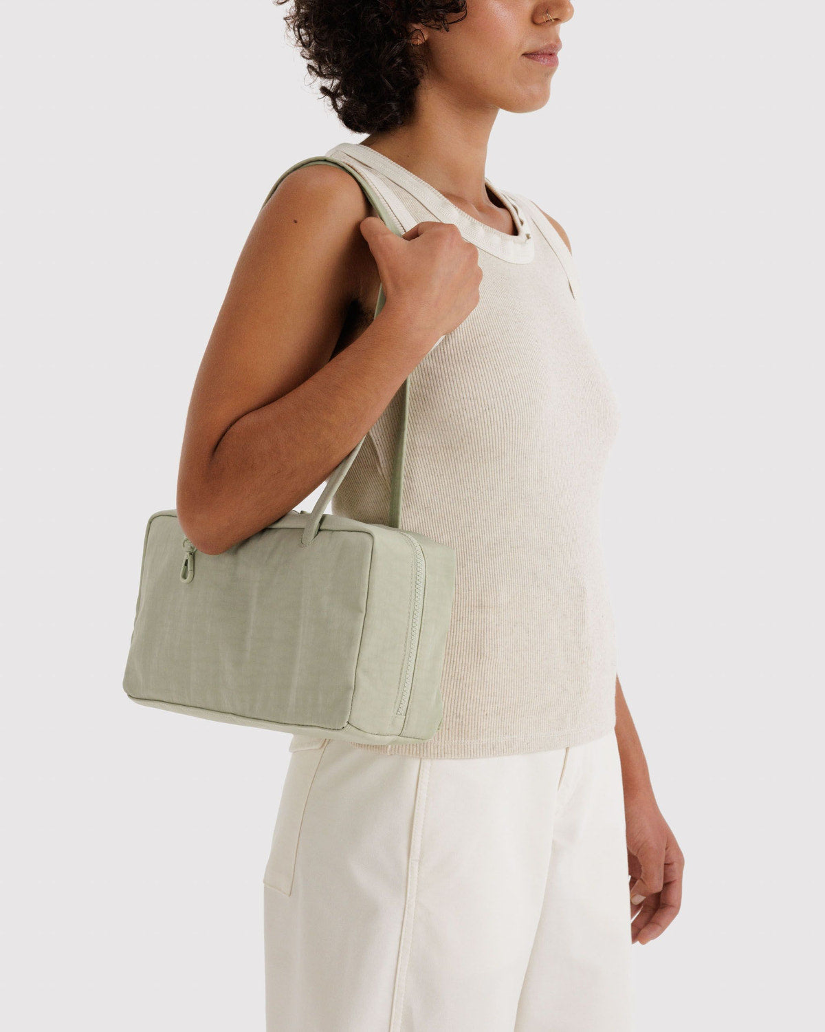 Sage green nylon bowler bag with top zipper and short handles, carried over shoulder