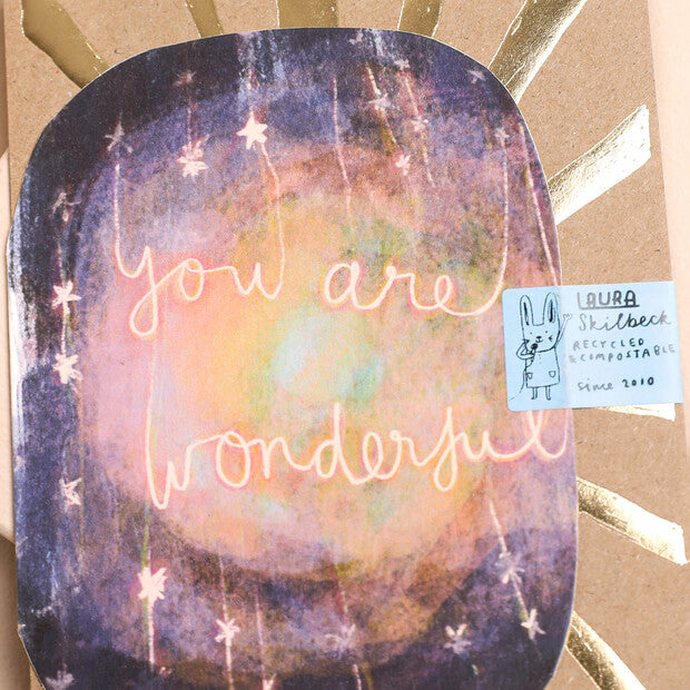 Close-up decorative greeting card front with “You are wonderful” neon script on galaxy