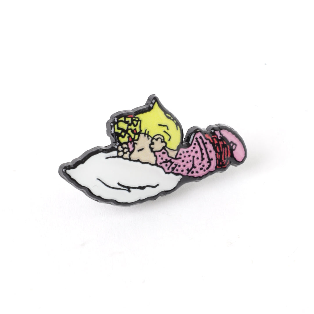 Character enamel pin with yellow and pink figure lying on a white shape, black outline