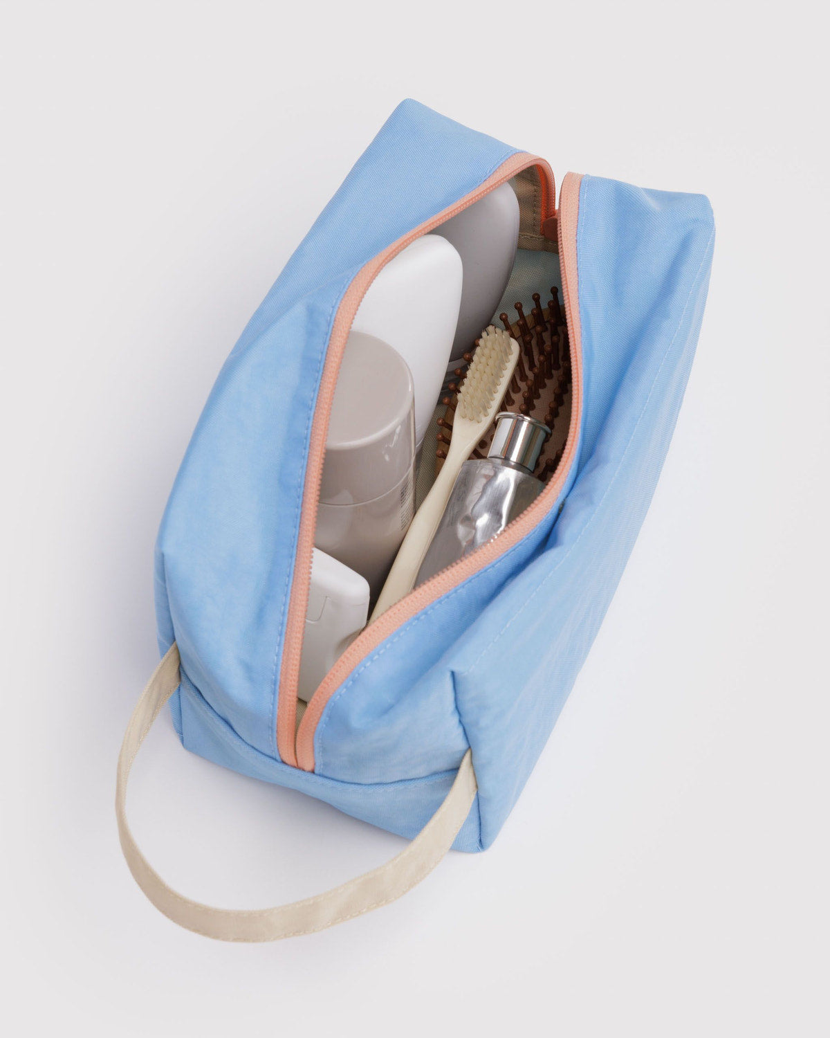 Light blue dopp kit open with toiletry bottles and brushes inside, zipper closure