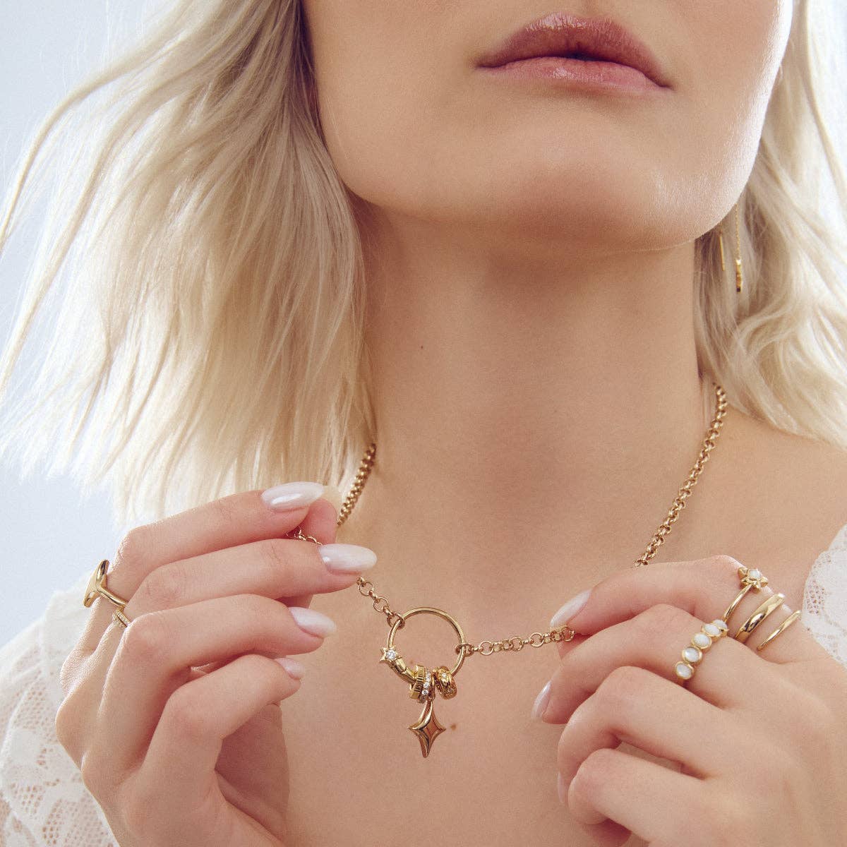 Gold star charm on chain necklace worn near face, with bracelets and rings