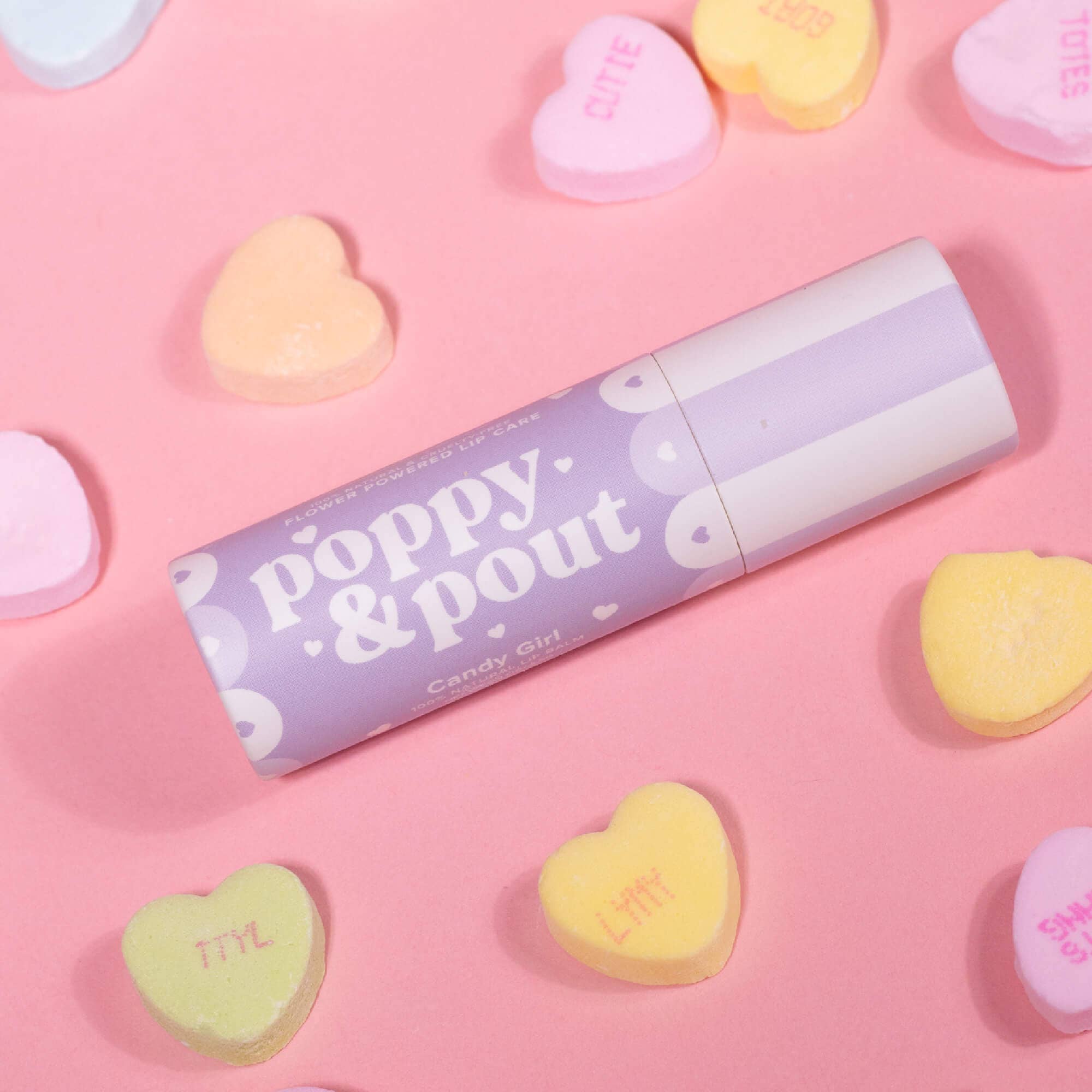 Candy Girl lip balm tube with purple label and heart shapes, angled view