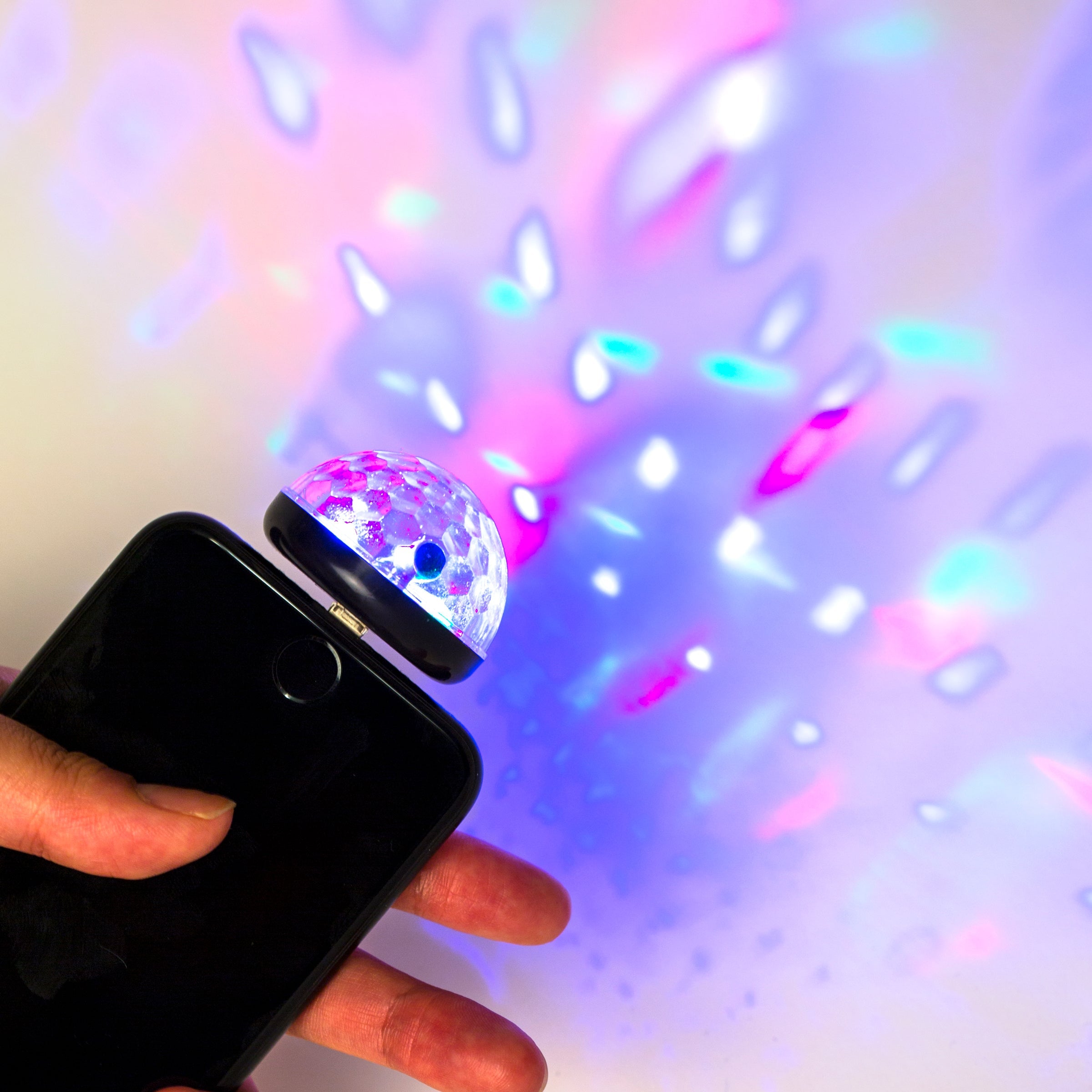 Phone disco light projecting colorful party patterns onto a wall, attached to phone