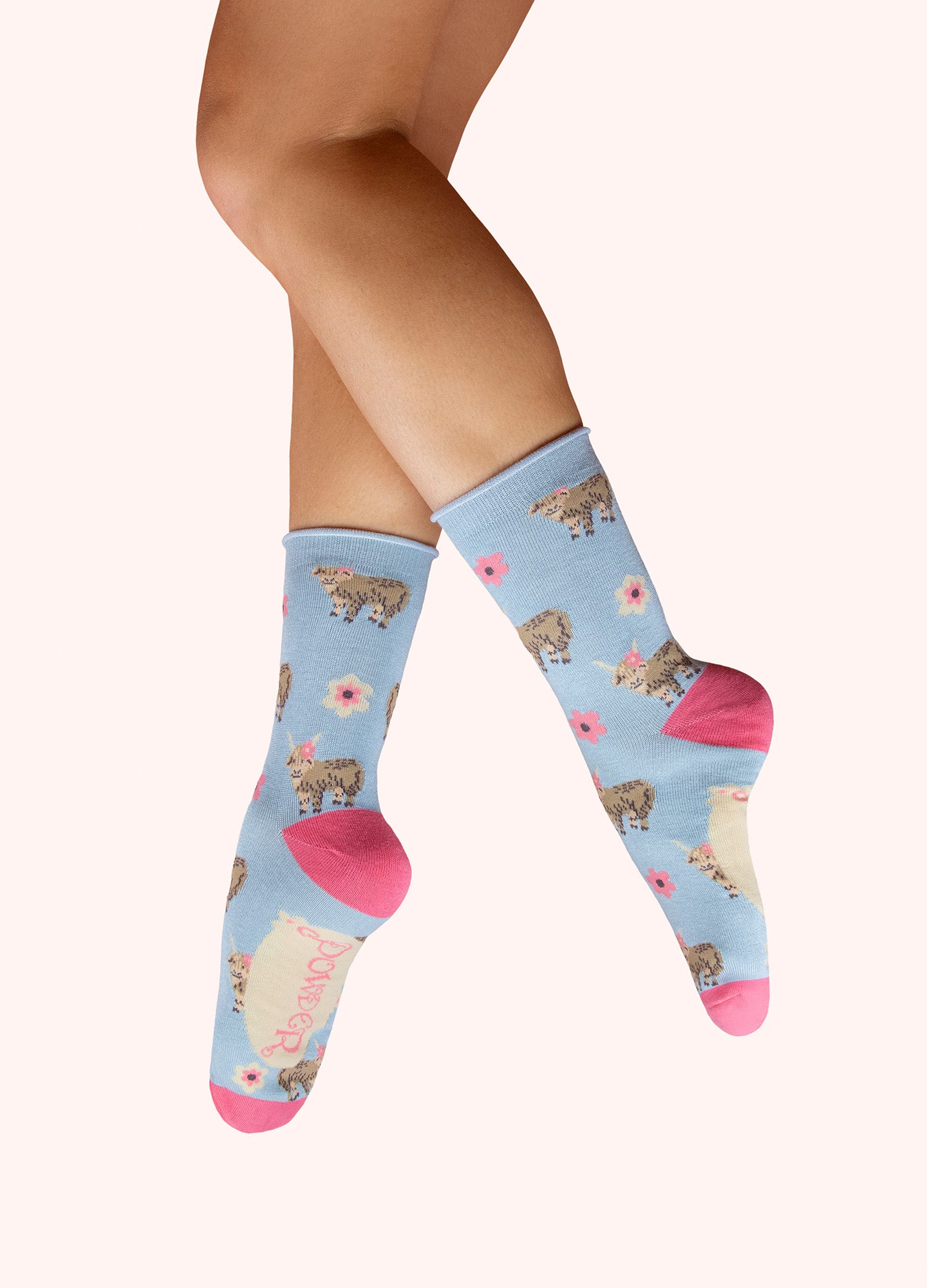 Light blue ankle socks with Highland cow print, flowers, and pink toe/heel accents