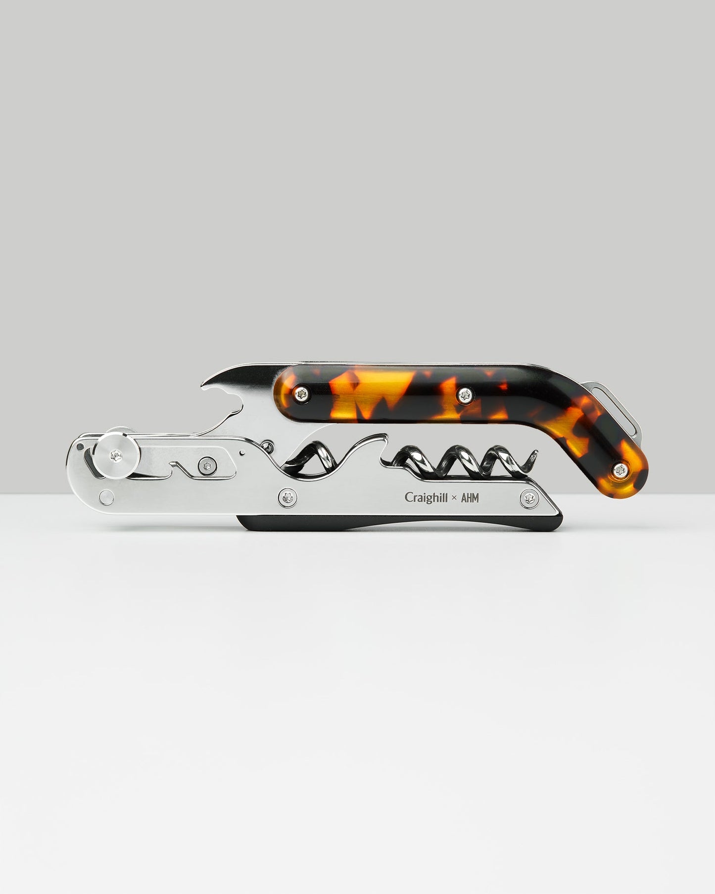 Silver wine key with amber tortoise body and corkscrew mechanism on side