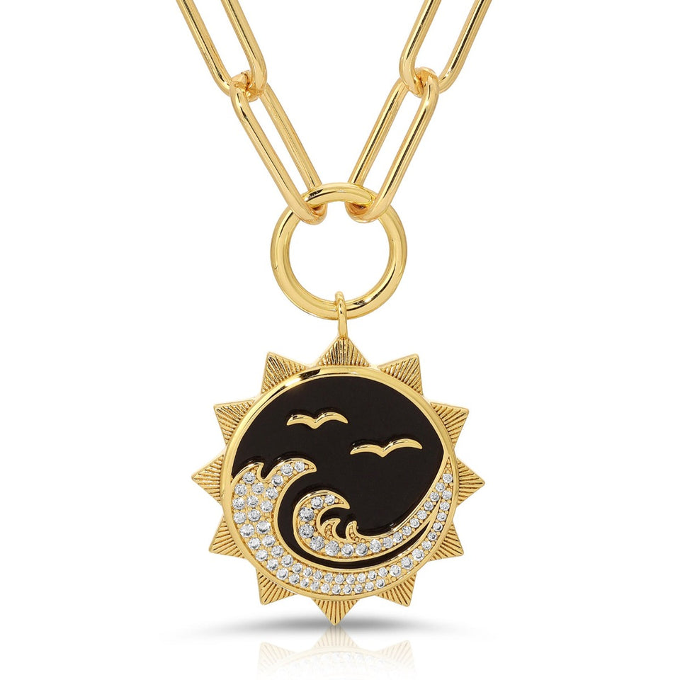 Gold-tone sun pendant with black onyx-style enamel and crystal accents on chain