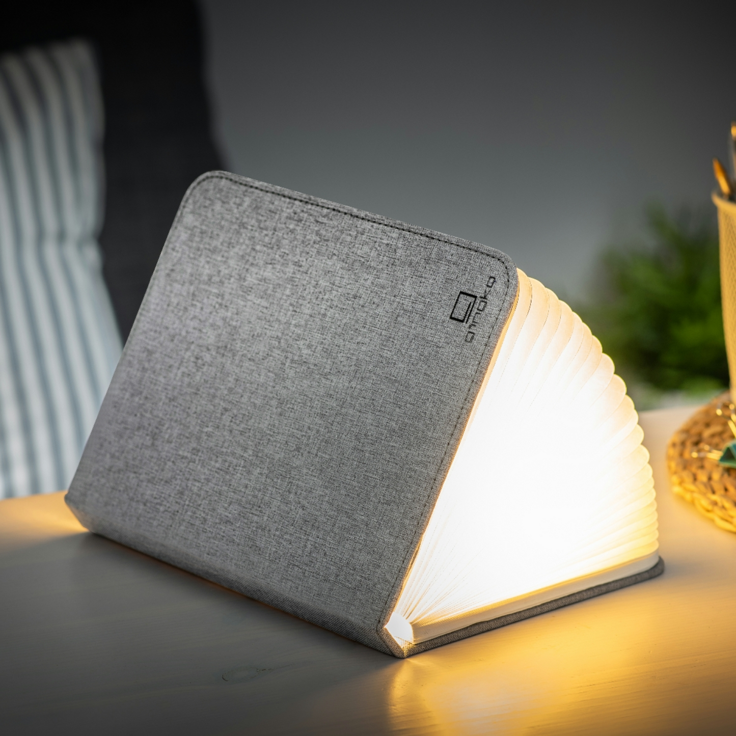 Gray linen smart booklight lighting up open pages on a compact angled base