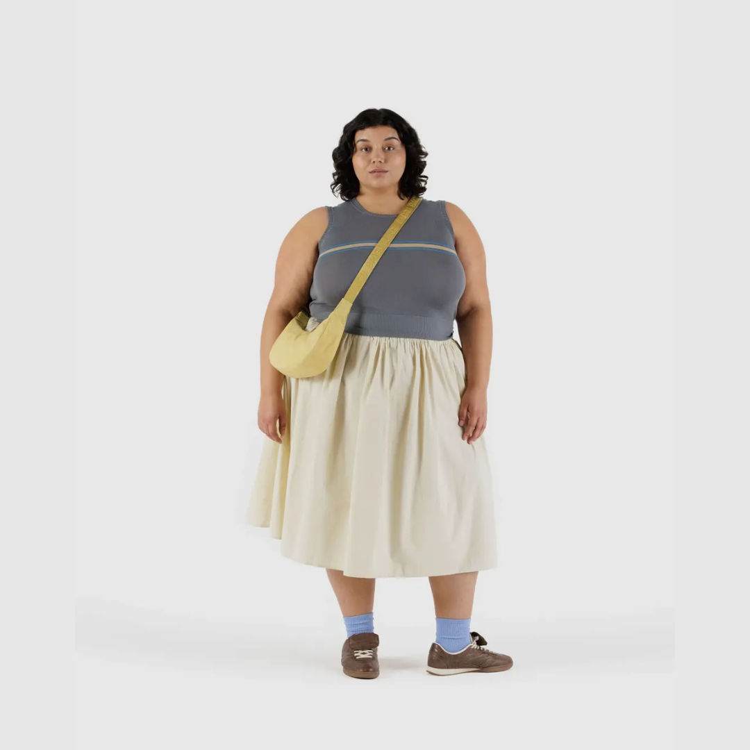 Small crescent nylon crossbody bag in light yellow worn crossbody with strap tag