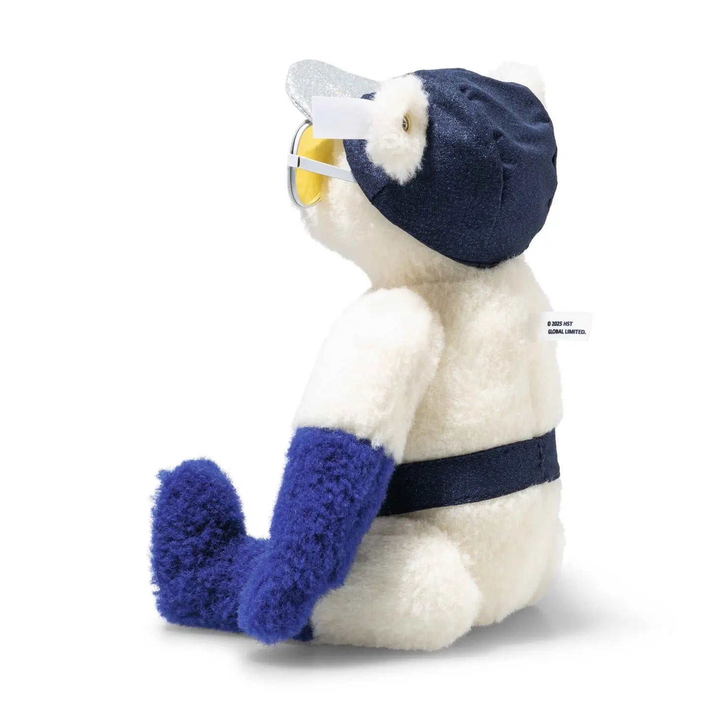 Cream teddy bear seated in navy cap with round yellow-tinted glasses