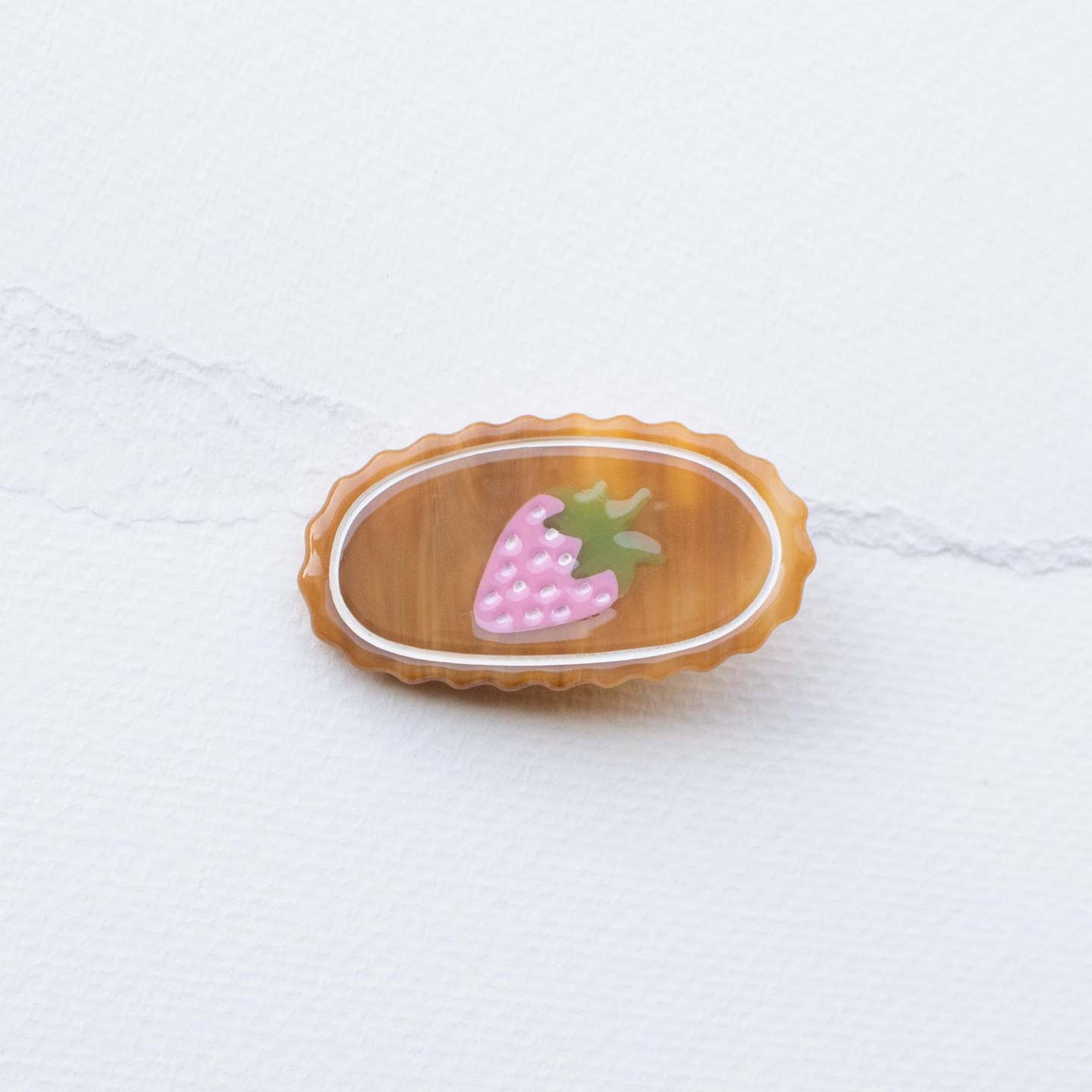 Oval acetate hair clip in dark wood tone with pink strawberry detail and green leaf