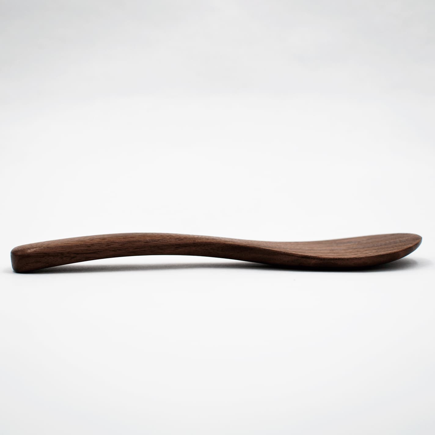 Walnut wood rice paddle with curved, elongated scoop for serving rice