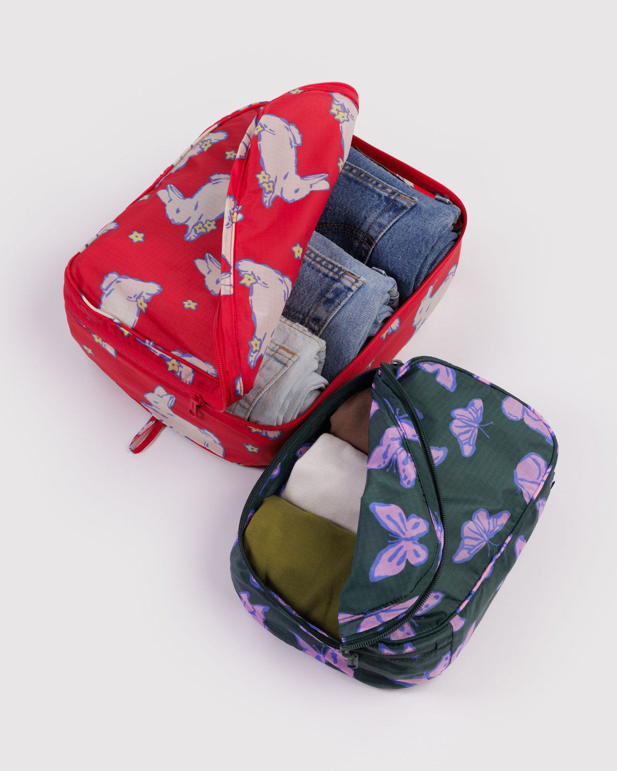 Packing cube set with red unicorn print and dark navy butterfly print, both open