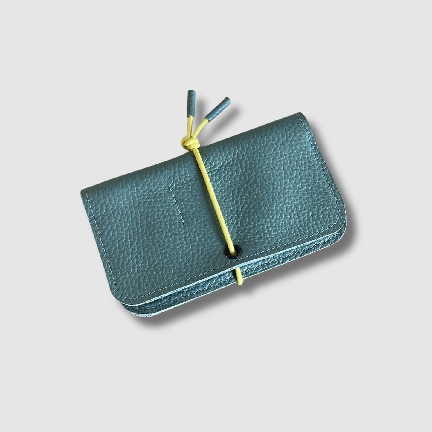 Teal leather knot wallet with front flap and yellow cord tie, pebble grain leather