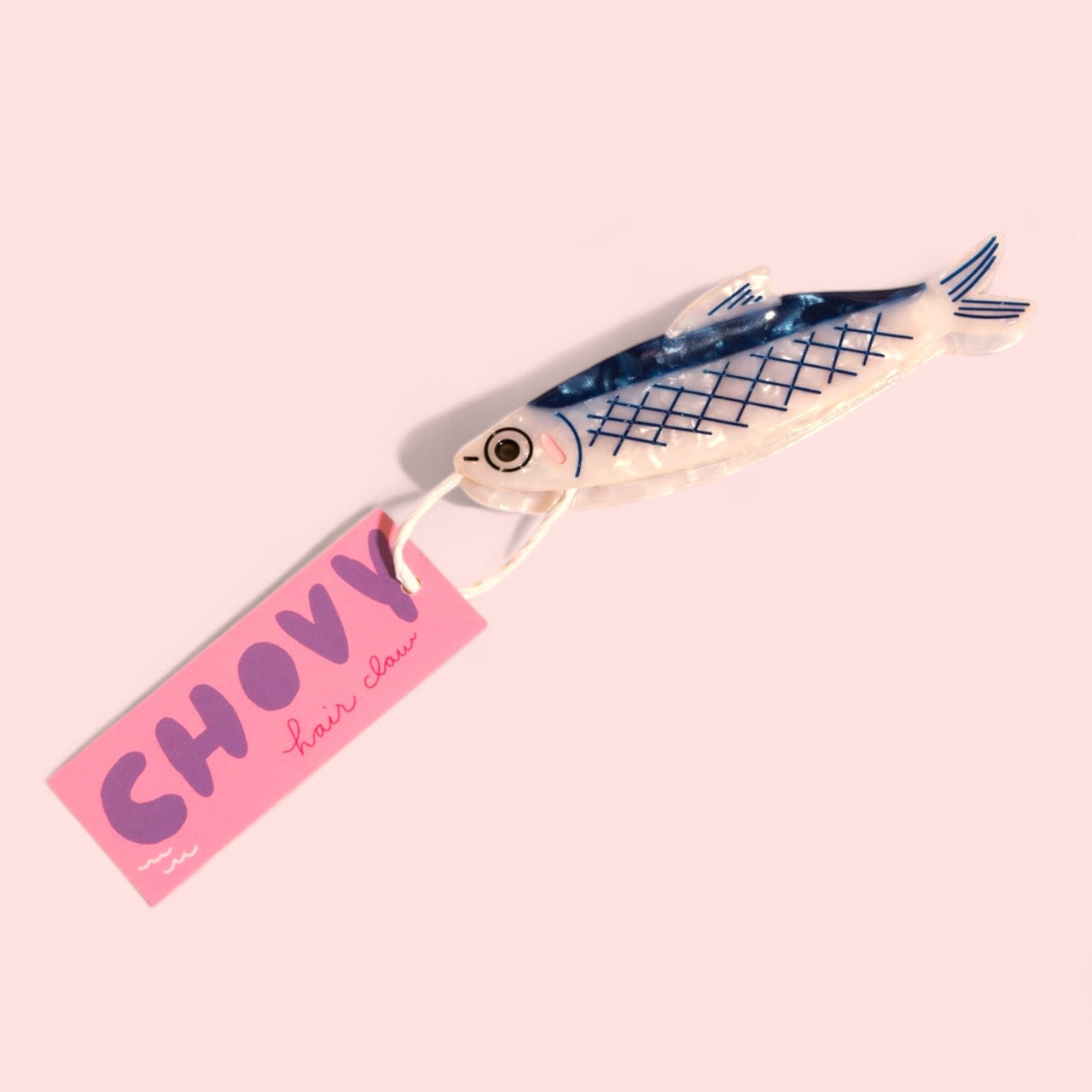 Fish-shaped hair claw with blue grid print on cream body, pink hanging tag