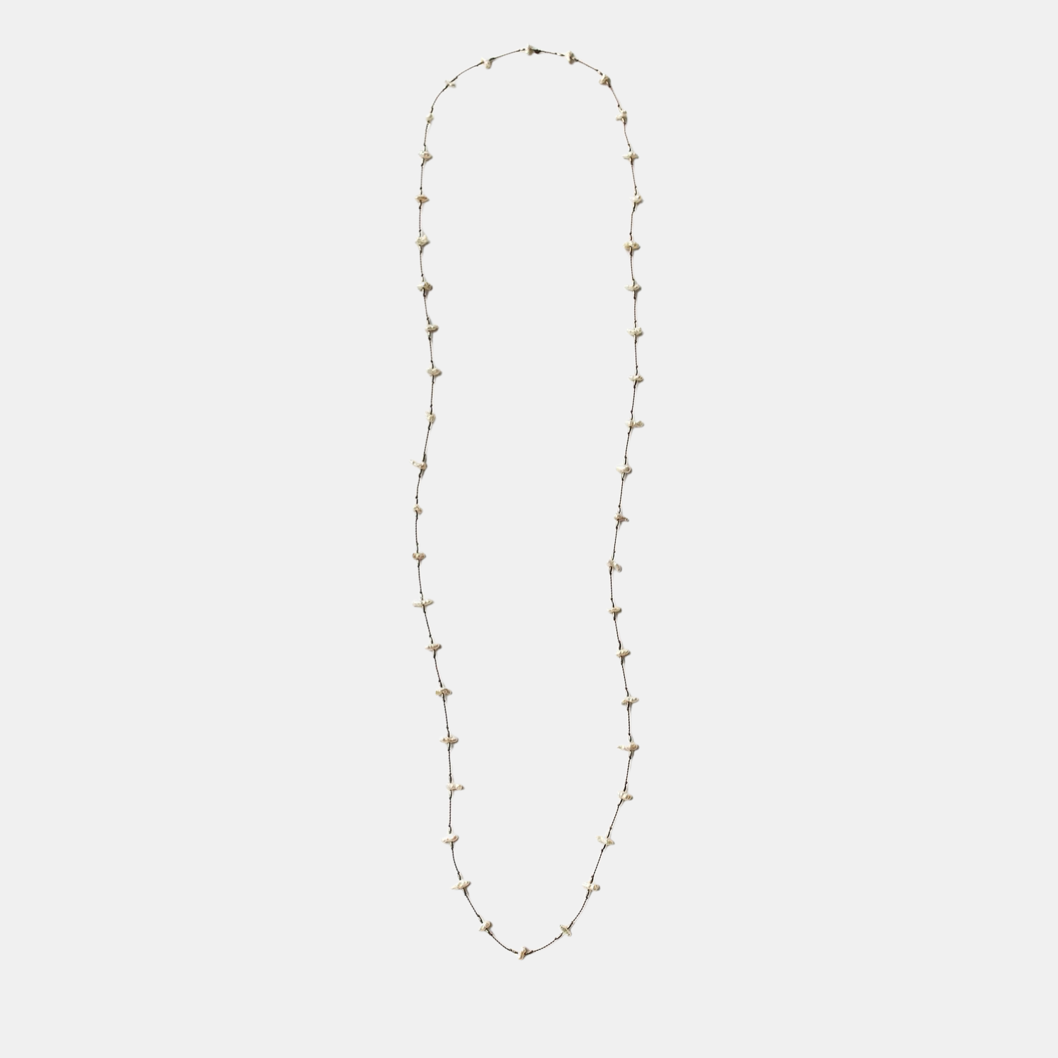 Long keshi pearl necklace with small white teardrop pearls on a thin gold-tone chain