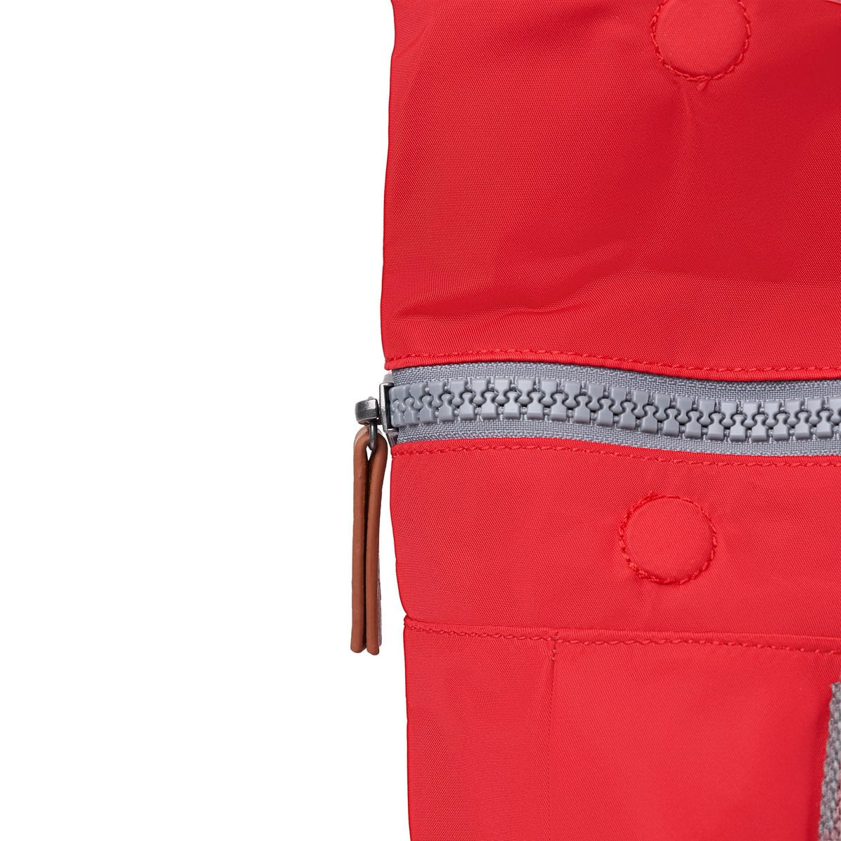 Red nylon backpack zipper edge with gray zipper track and brown zipper pull tab