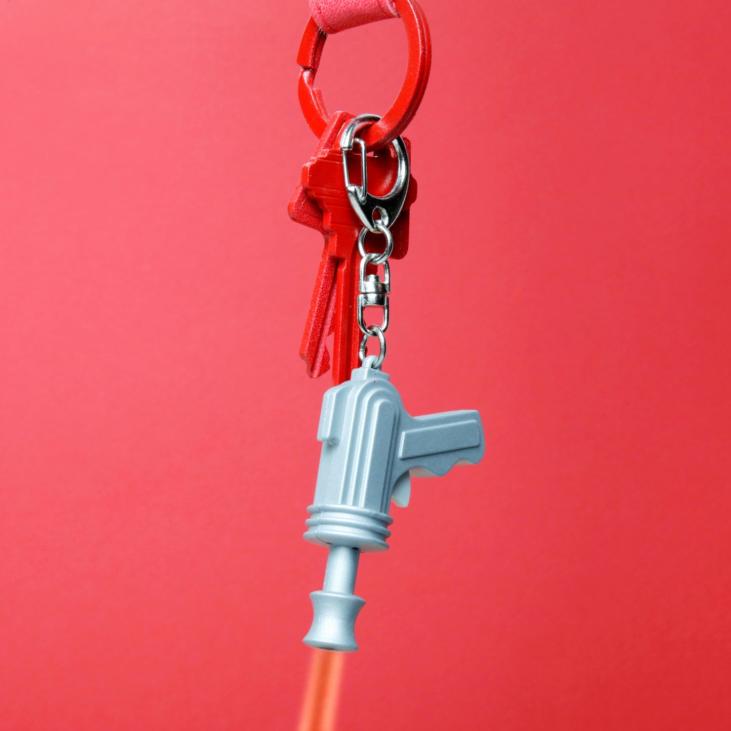 Space gun keychain detail, light blue pistol charm on red key ring