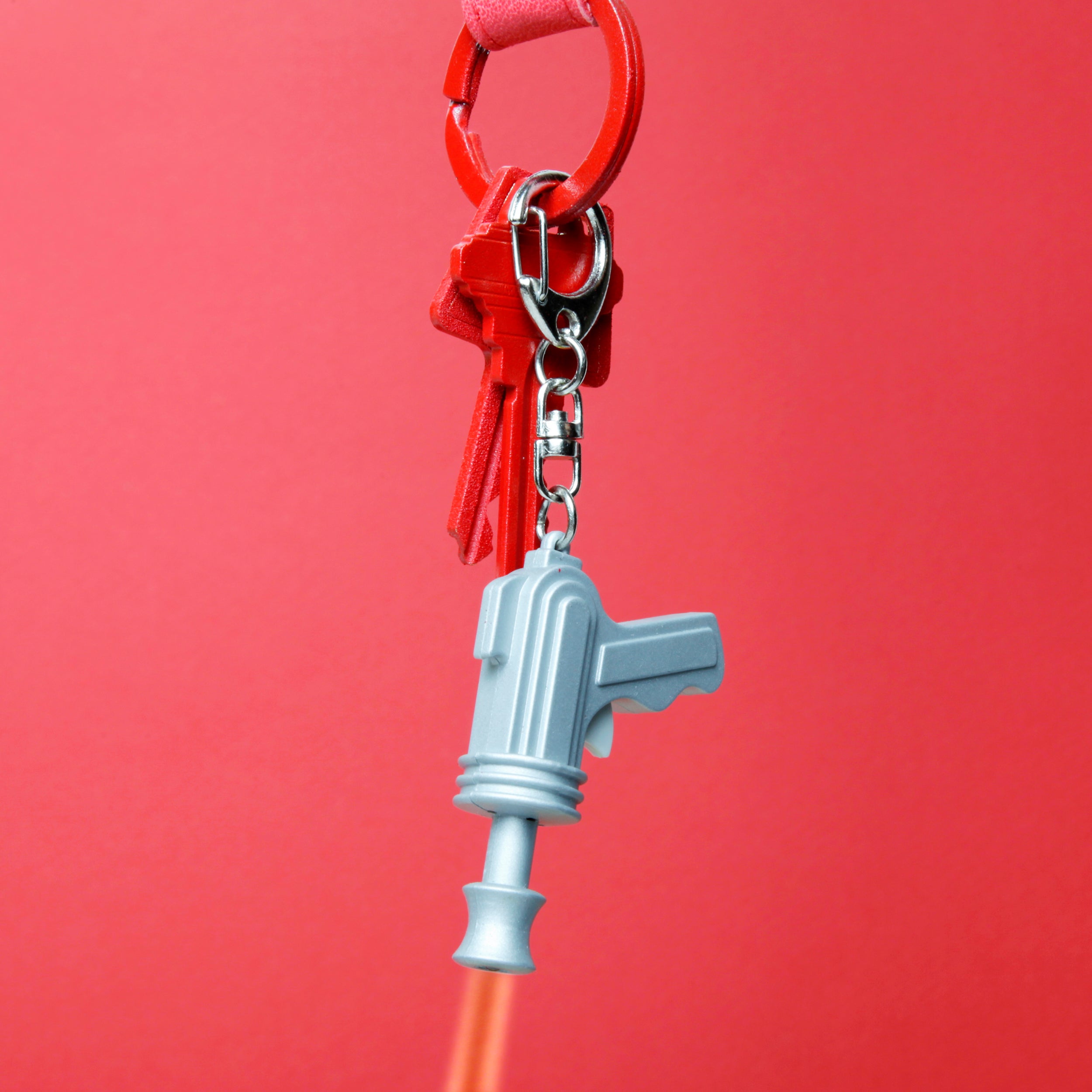 Space gun keychain detail, light blue pistol charm on red key ring
