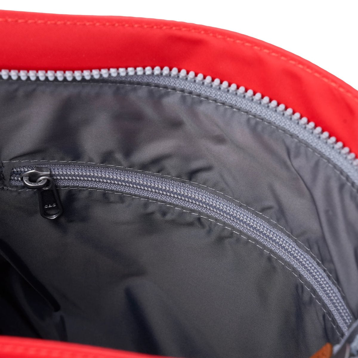 Red nylon crossbody interior with black lining and gray zipper pull