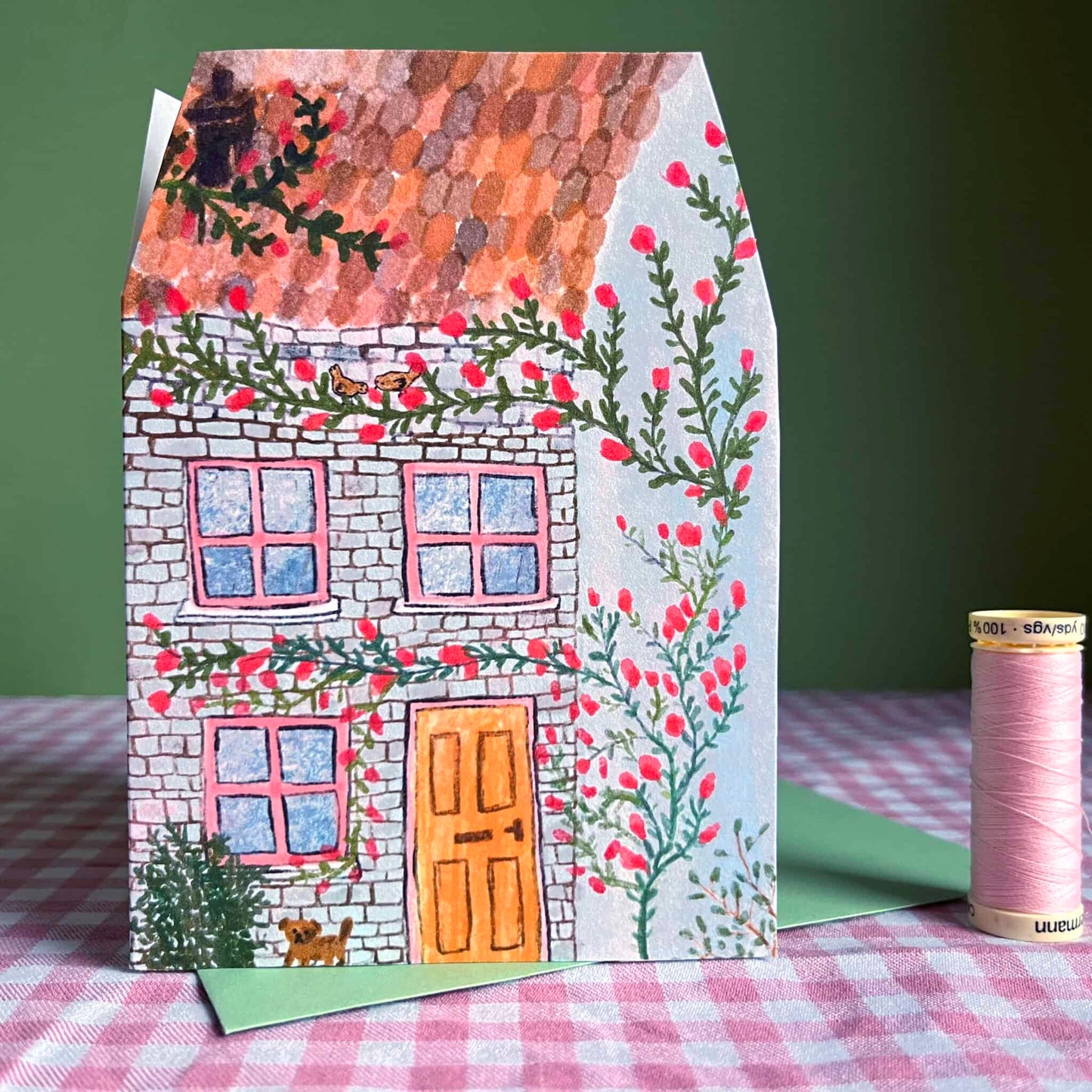 House greeting card with brick facade, blue windows, orange door, flowers and vines