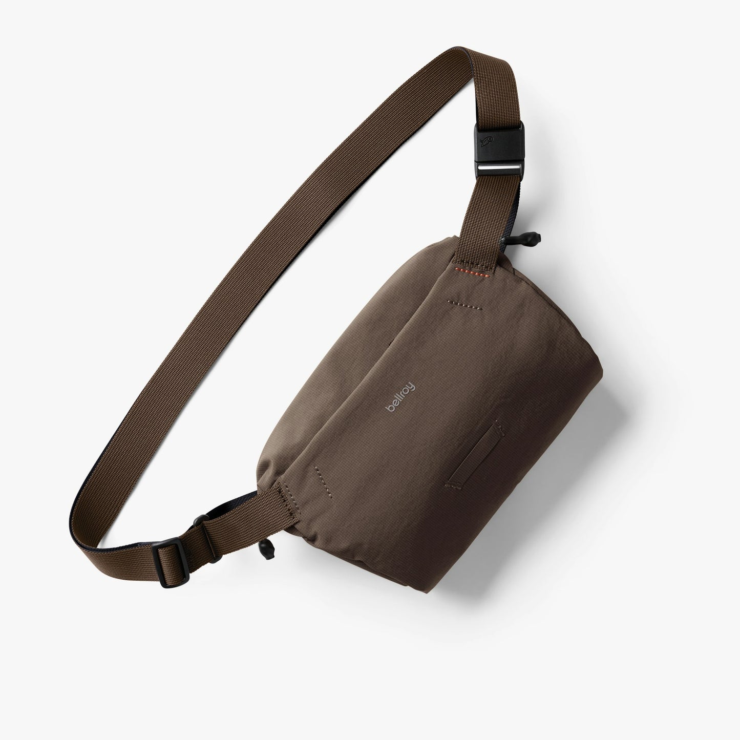 Mini sling bag in dark brown with adjustable strap and front zip pocket.