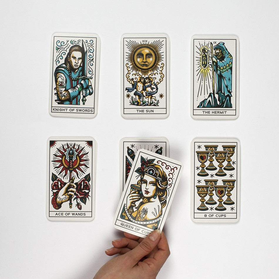 Tarot card spread on a table; hand holds the Queen of Cups card