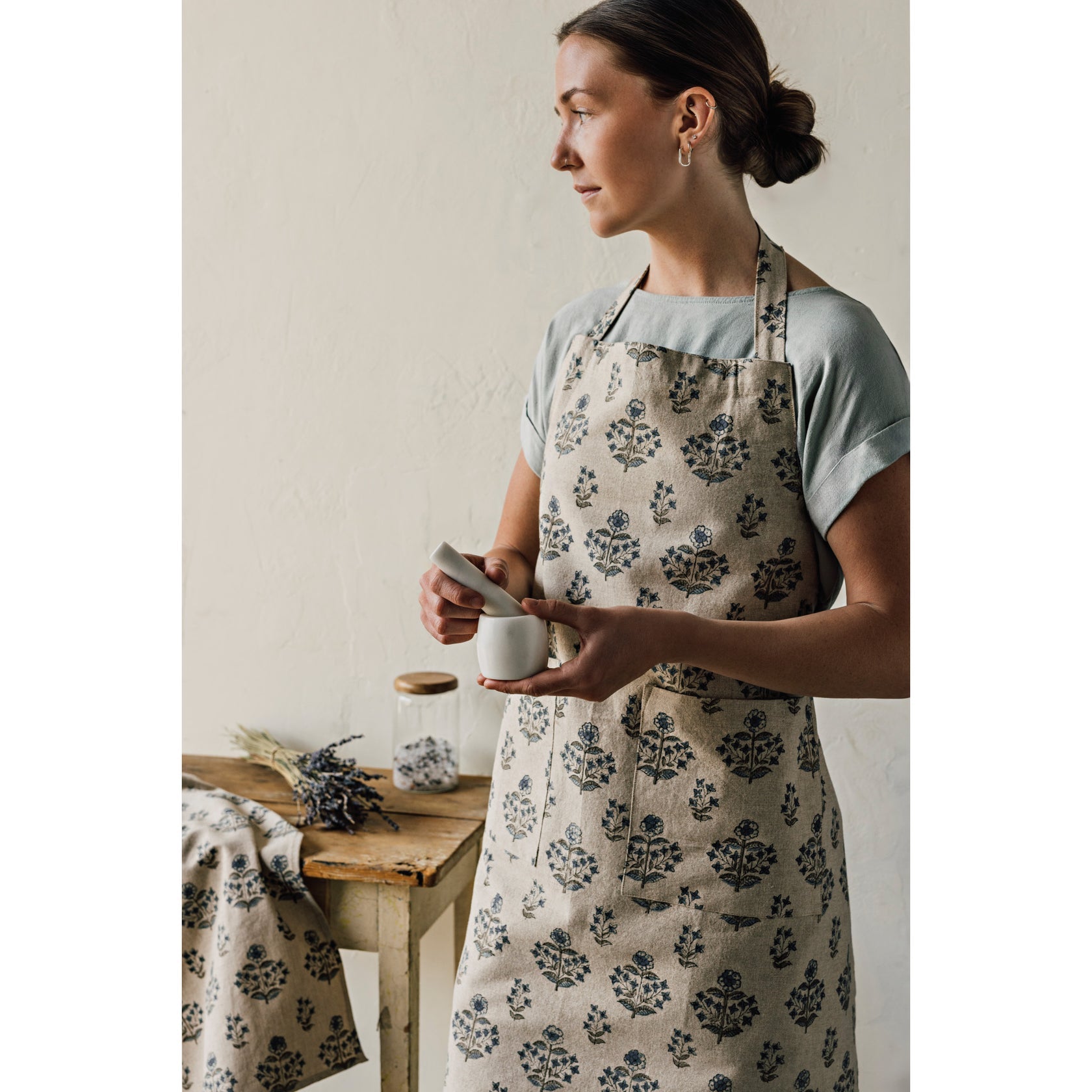 Apron worn by model: cream fabric with blue-green block floral print and neck tie