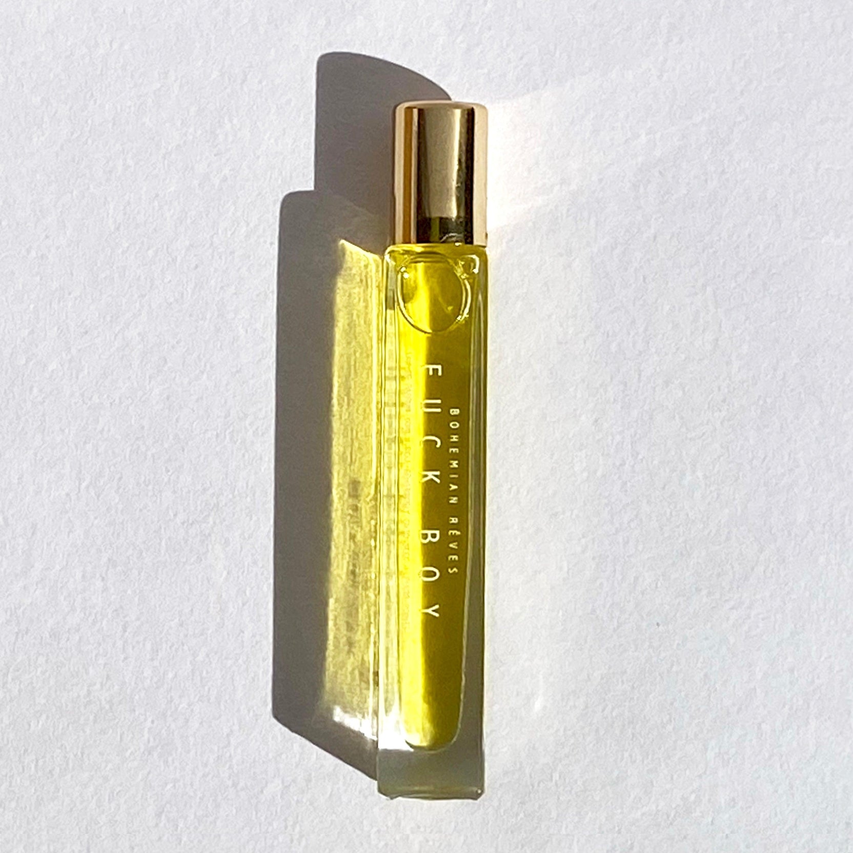 Gold perfume roller bottle with metallic cap, amber liquid, rectangular label