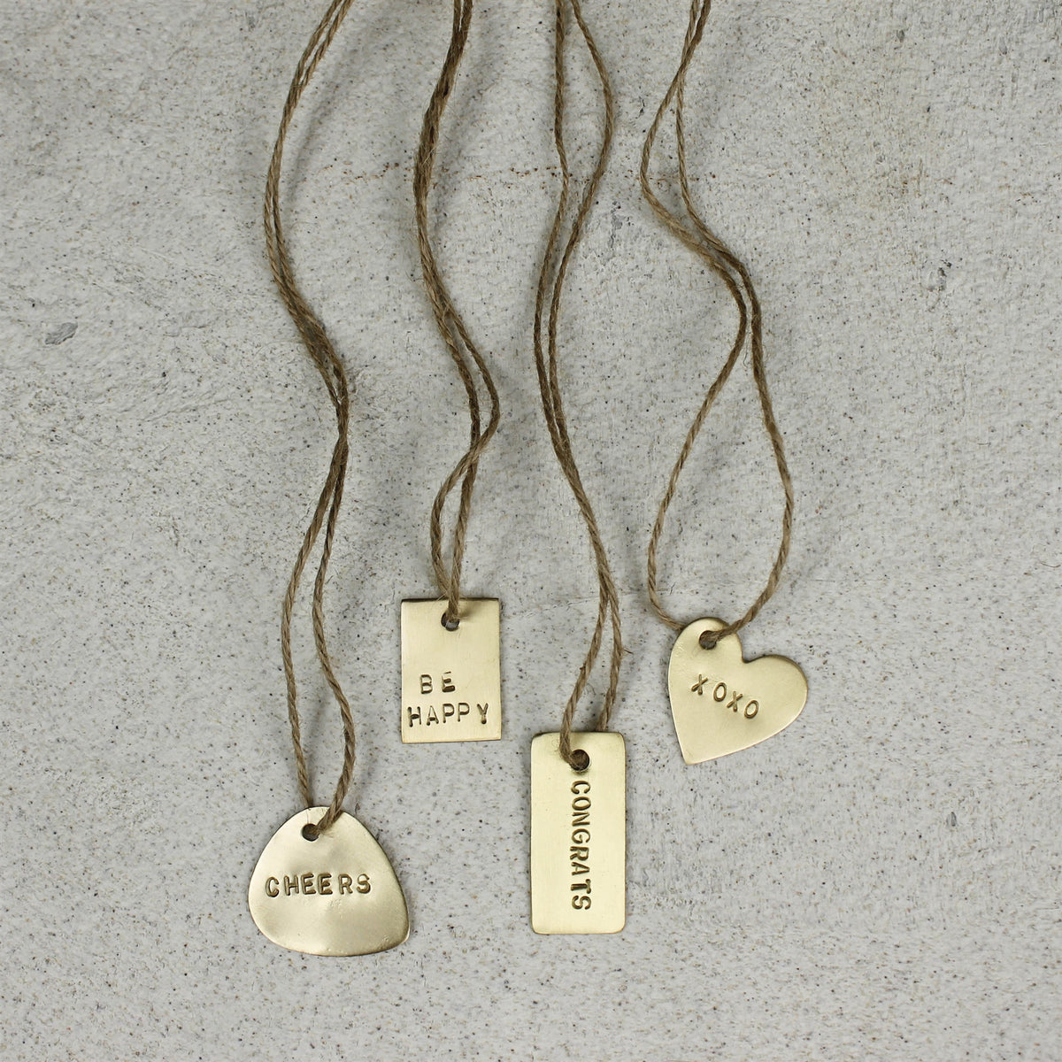 Brass charm tags on cords, including a heart "xoxo" tag and three others