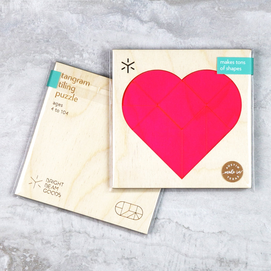 Pink heart tangram puzzle set with cardboard pieces and heart-shaped cover