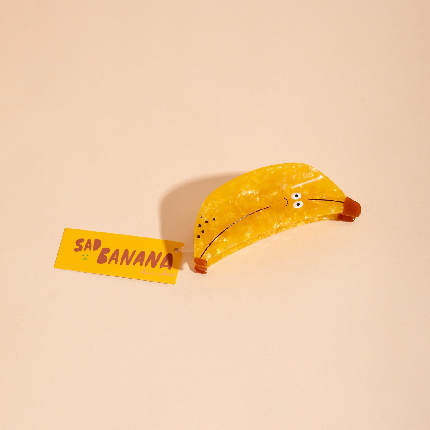 Yellow banana hair claw with speckled surface and curved open clamp