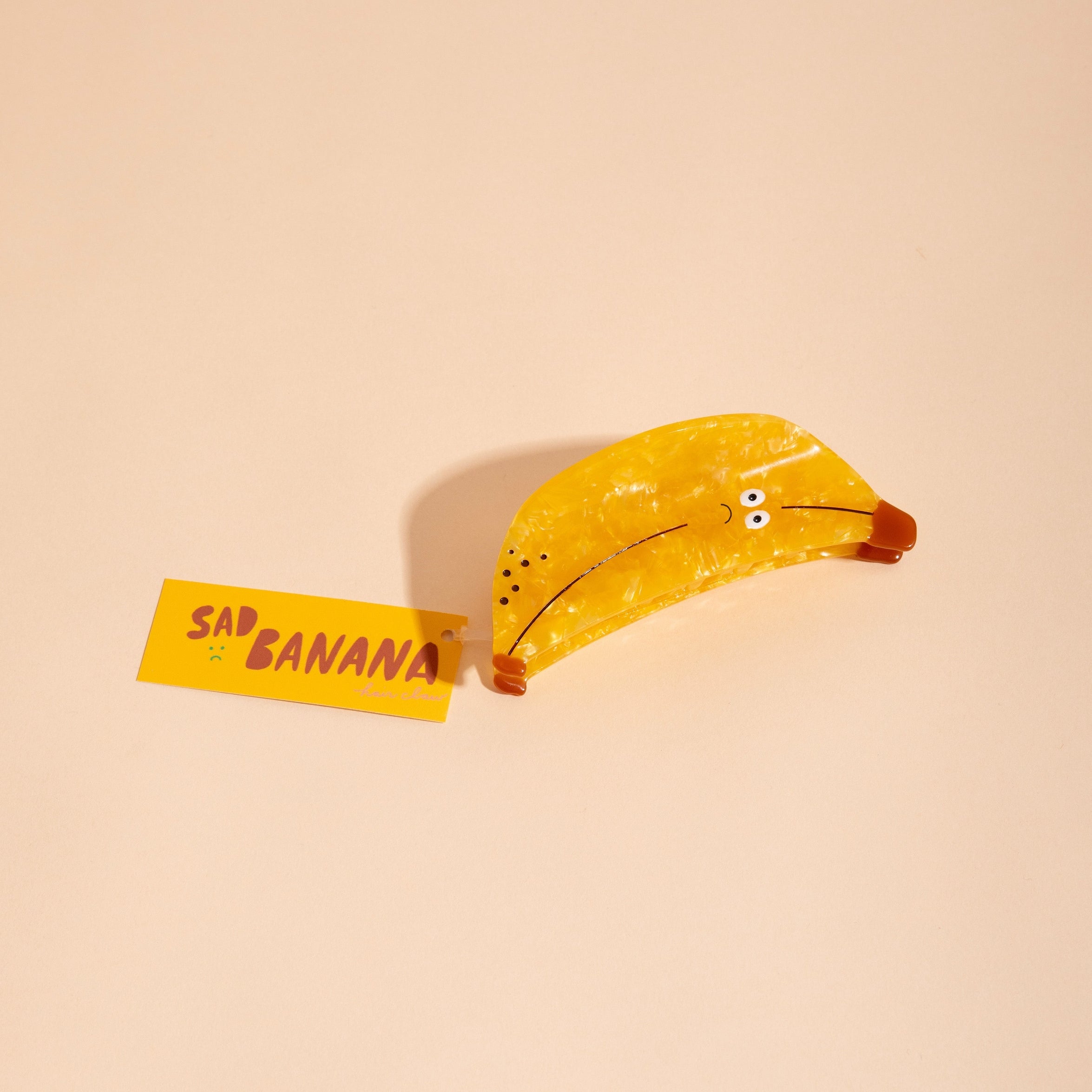 Yellow banana hair claw with speckled surface and curved open clamp