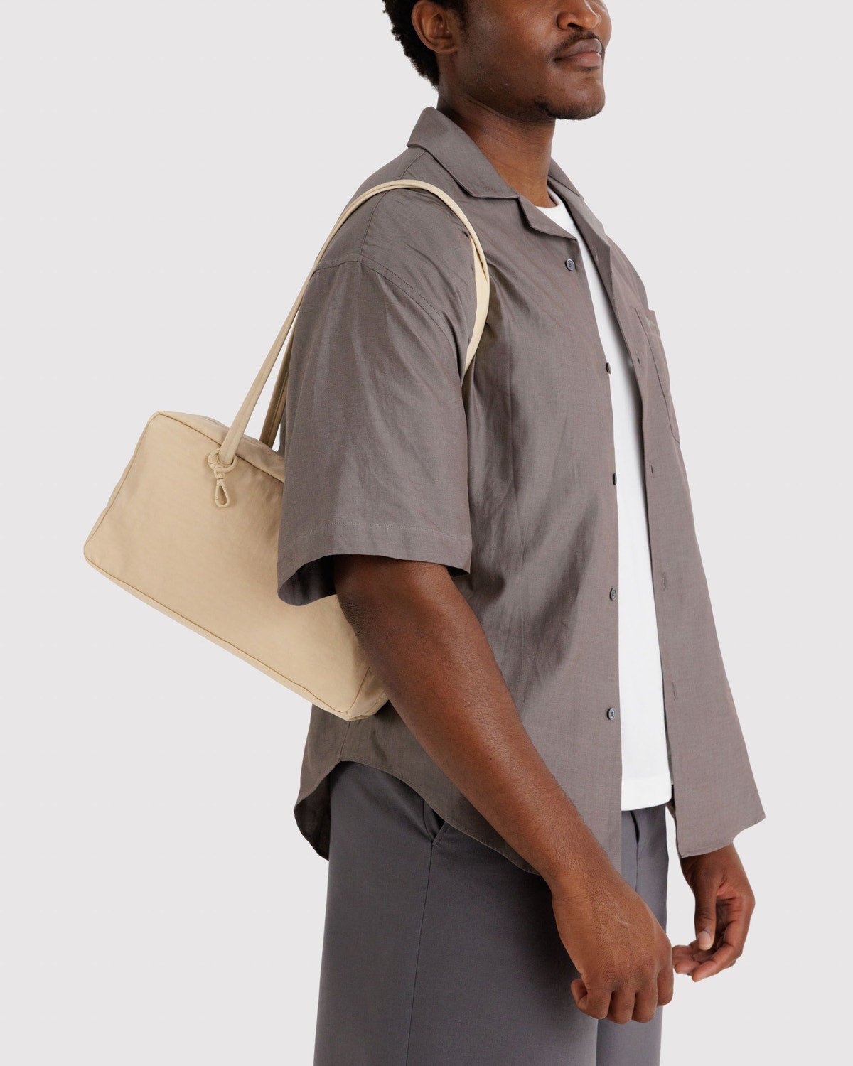 Tan nylon bowler bag with top zipper and short handles, worn at side