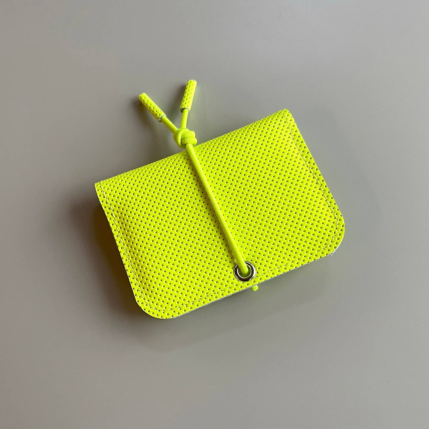 Neon yellow leather mini wallet with knot closure and textured exterior