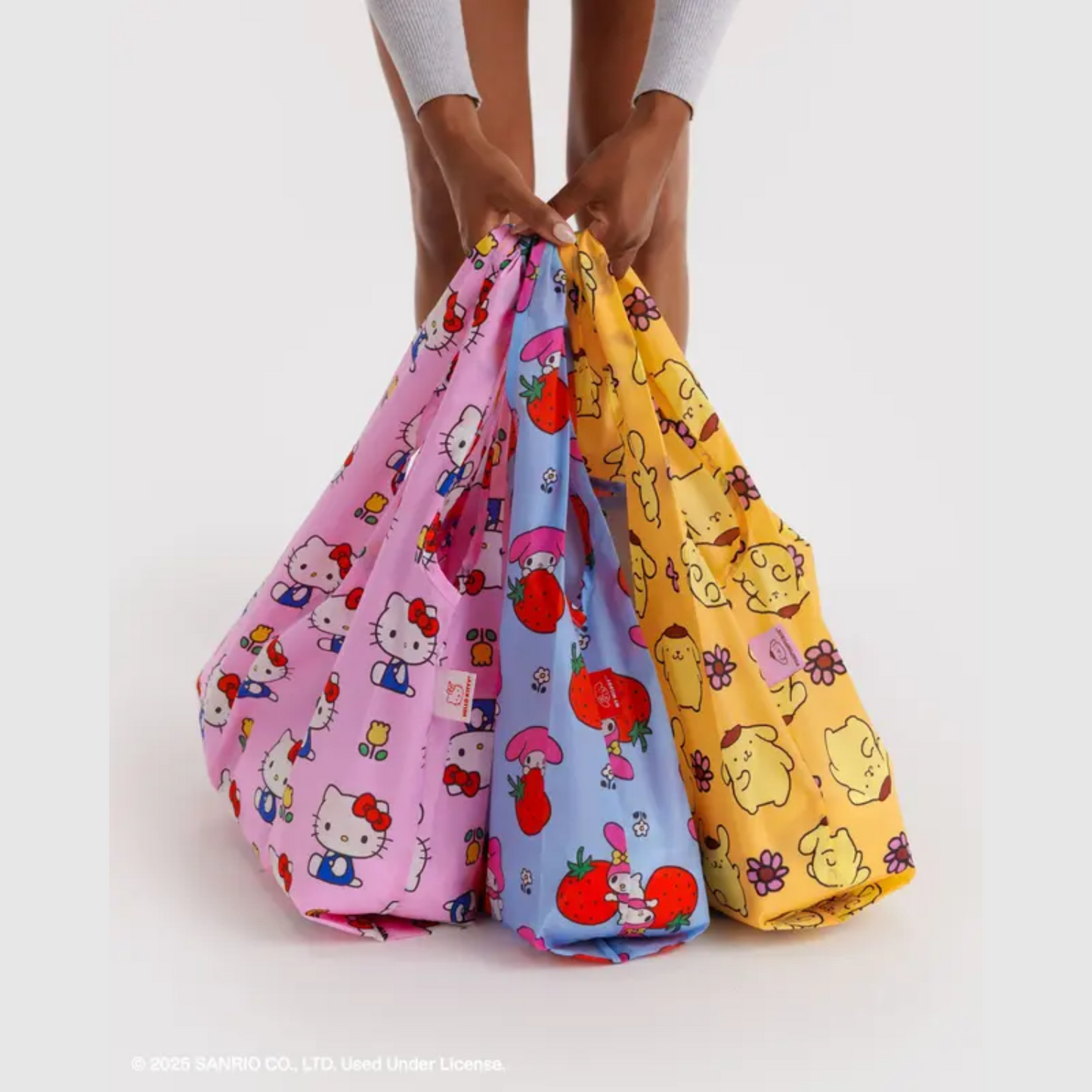 Three character-print drawstring pouches held together in pink, yellow, and multicolor