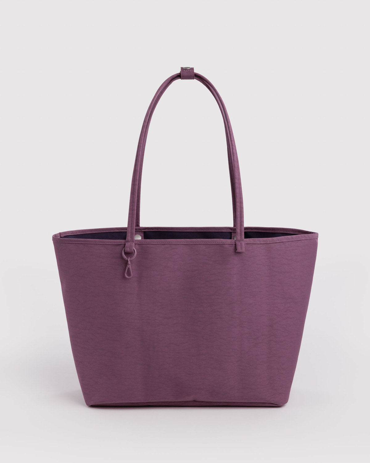 Large nylon reversible tote in plum purple with top handles and zip pocket tab