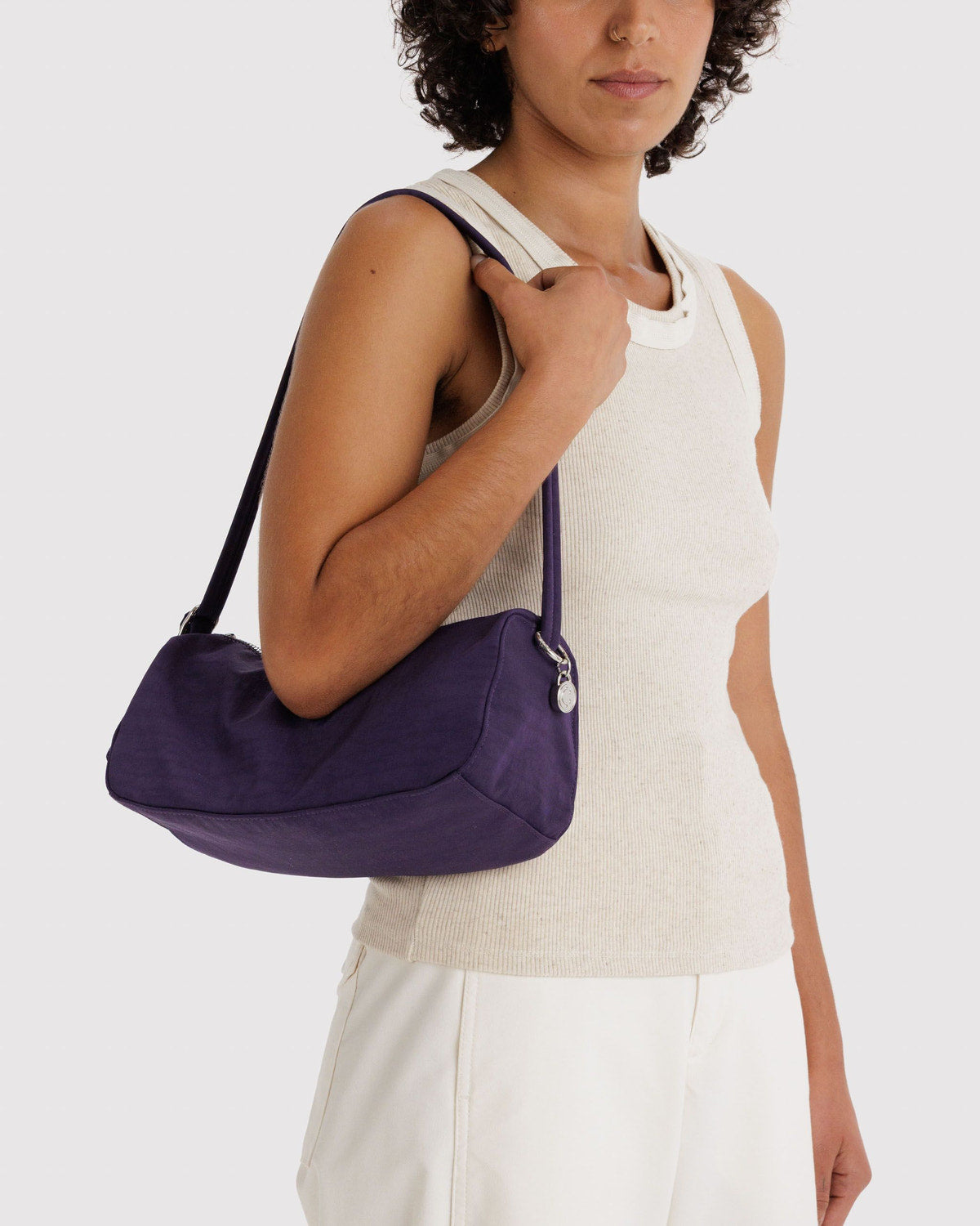 Fig nylon loaf bag worn over shoulder; curved handle, side strap, top zipper.