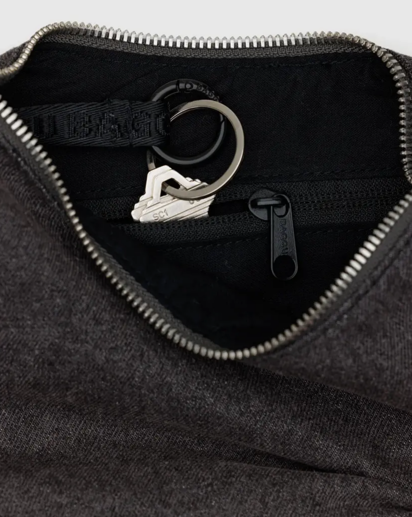 Black denim crescent bag interior with zipper, ring clip, and fabric lining detail
