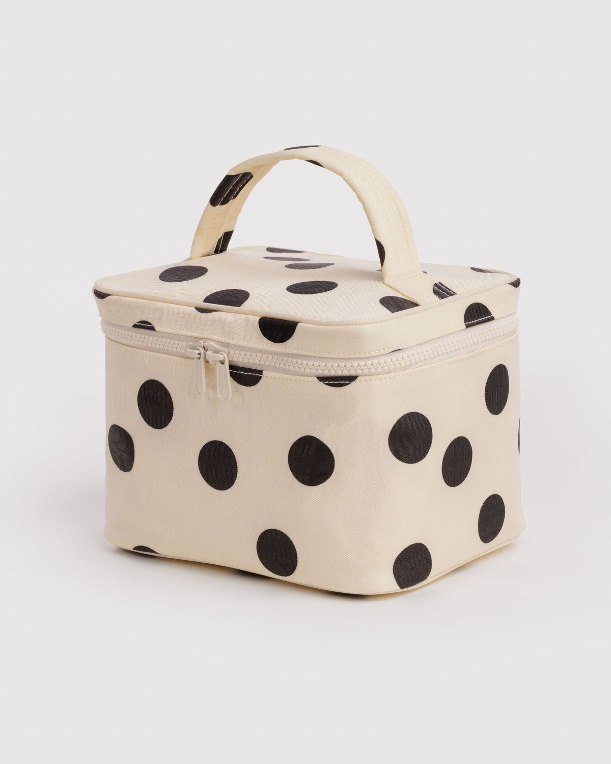Large cream cosmetic case with black polka dots and top handle, zip closure.