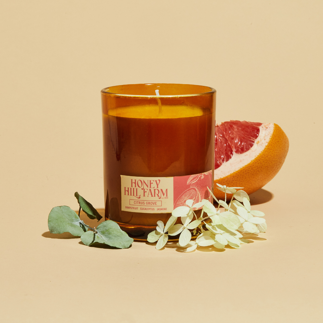 Amber glass candle with 'Honey Hill Farm' label, with grapefruit slice and white blossoms