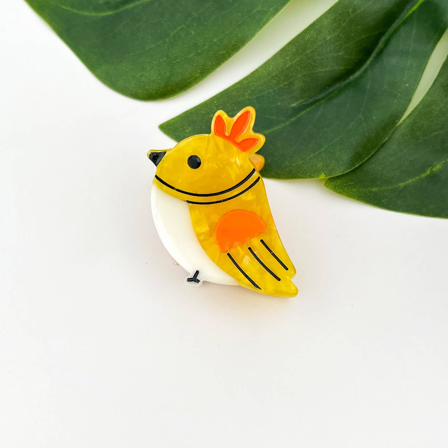 Yellow bird hair claw clip with orange crown, black beak, and red accent