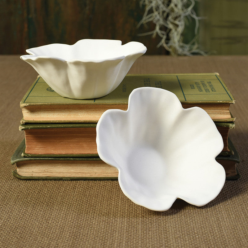Set of two white hibiscus floating tealight holders on stacked books