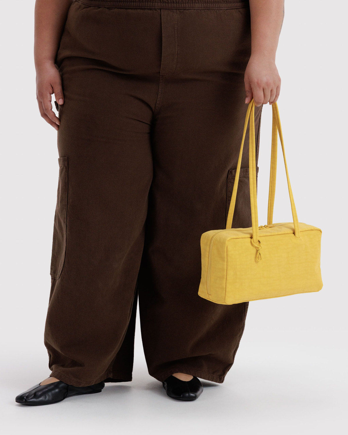Nylon bowler bag in butter yellow, shown carried at side with top handles