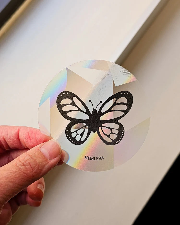 Round iridescent butterfly suncatcher with black cutout-style butterfly design